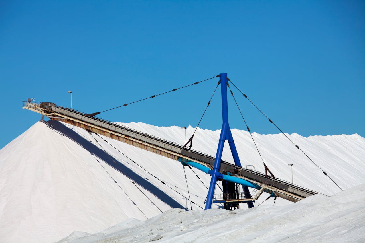Conveyor system in a salt mining landscape under a clear blue sky.
